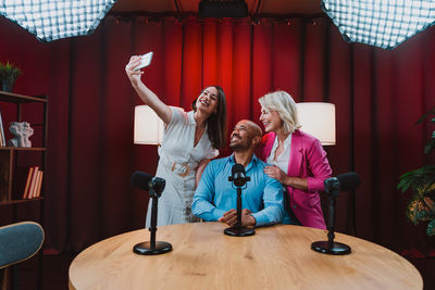 Full length of woman with arms raised sitting on table