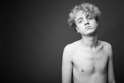 Portrait of shirtless man standing against black background