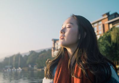 Young woman with eyes closed against sky