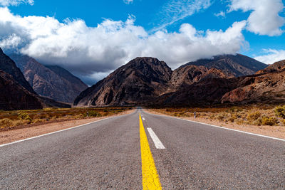 Road by mountains against sky