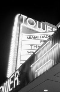 Low angle view of illuminated sign on building at night