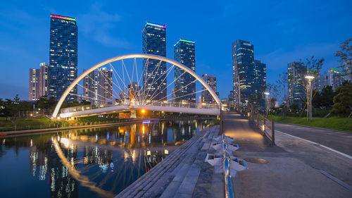 Illuminated bridge and buildings against sky at night