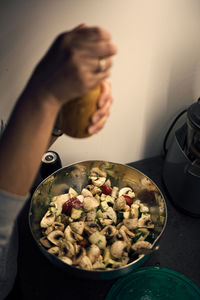 Cropped hand of person holding pepper mill over food in pan