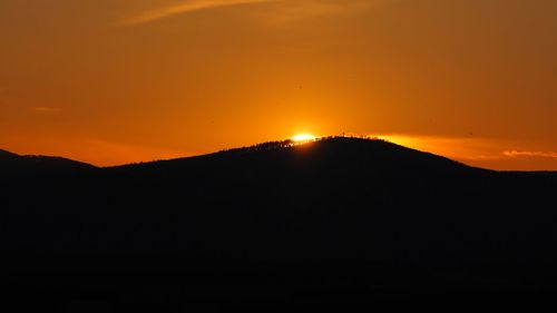 Scenic view of silhouette mountains against orange sky