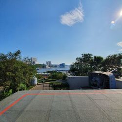 Road by building against blue sky