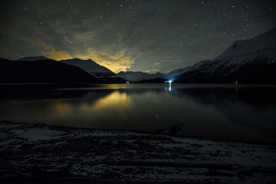 Scenic view of lake and mountains against star field in sky