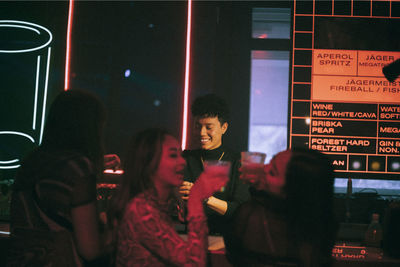 Cheerful non-binary person clubbing with friends at nightclub