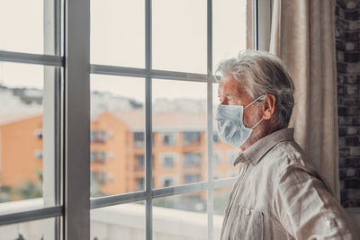 Side view of man looking through window