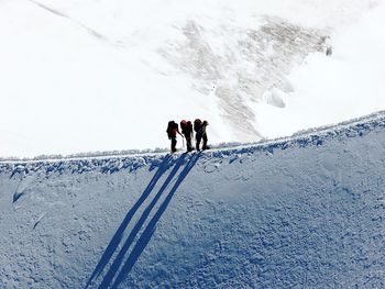 Hikers walking on ridge of snowcapped mountain