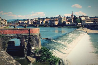 View of city by river against sky