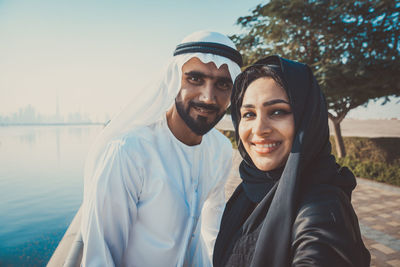 Portrait of smiling couple wearing traditional clothing standing against sky