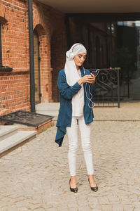Full length of woman holding mobile phone outdoors