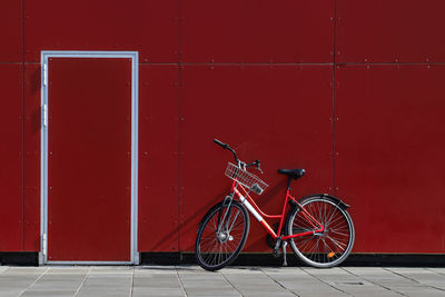 Bicycle parked against red wall