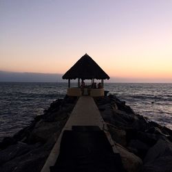 Lifeguard hut on beach against sky during sunset