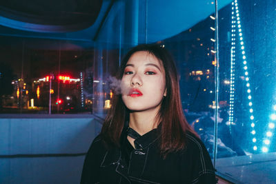 Close-up of young woman smoking at night