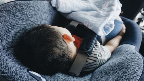 High angle view of boy sleeping in car seat for safety 