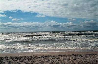 Scenic view of beach against cloudy sky