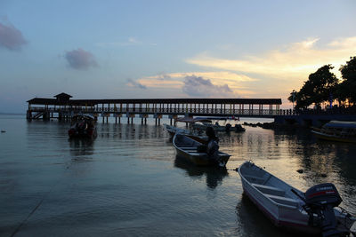 Boat moored on sea against sky during sunset