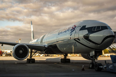 Airplane on airport runway against sky