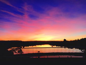 Silhouette bridge over river against sky during sunset