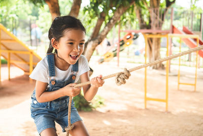 Girl holding rope while playing in playground