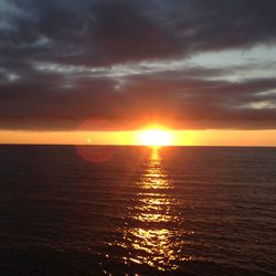 Scenic view of sea against dramatic sky during sunset