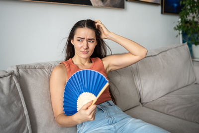 Portrait of young woman sitting on sofa at home