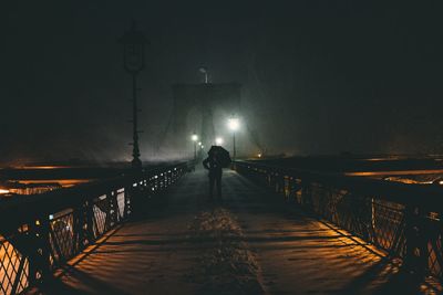 Mid distance view of person standing on brooklyn bridge at night