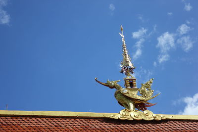 Low angle view of sculptures on roof of building against sky