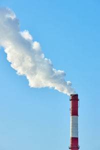 Low angle view of smoke emitting from chimney against sky