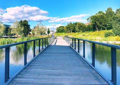 Footbridge amidst trees against sky