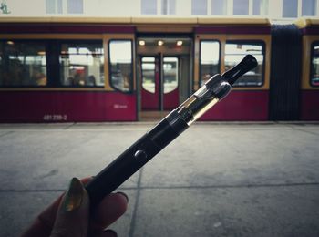 Cropped image of hand holding electronic cigarette at railroad station