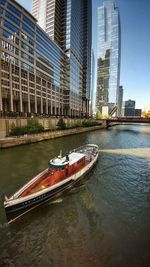 Modern buildings by river in city against sky