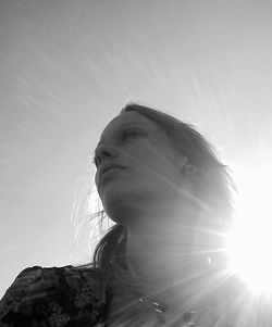 Low angle view of sun shining through clouds