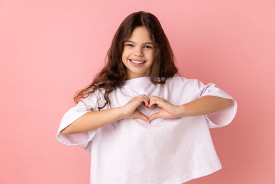 Portrait of young woman holding gift against pink background