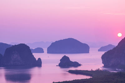 Rocks in sea against sky during sunset