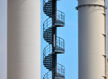 Metal spiral staircase on an industrial building with two chimneys