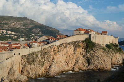 Houses by sea against sky