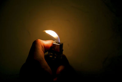 Close-up of hand holding lit candle in the dark
