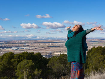 Young woman standing against sky