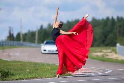 Rear view of woman holding umbrella while standing on road