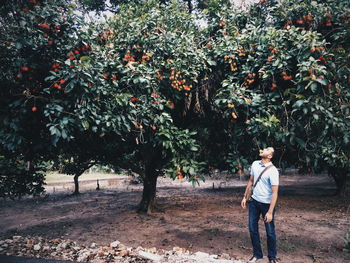 Full length of young man eating fruit from tree