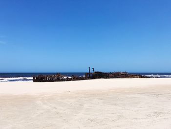 Scenic view of beach against clear blue sky