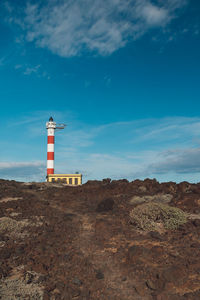 Lighthouse on street amidst buildings against sky