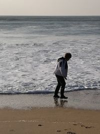 Full length of man standing on beach against sky