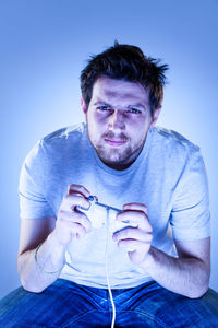 Portrait of mid adult man sitting against blue background