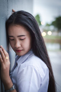 Close-up of young woman standing by wall