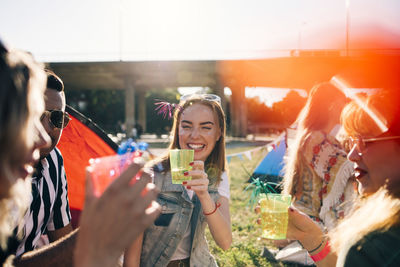 Smiling friends enjoying drinks in music concert during summer