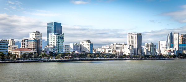 Sea by buildings against sky in city