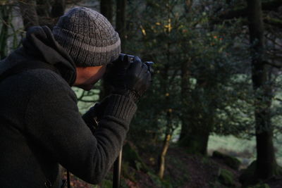 Midsection of man holding tree in forest